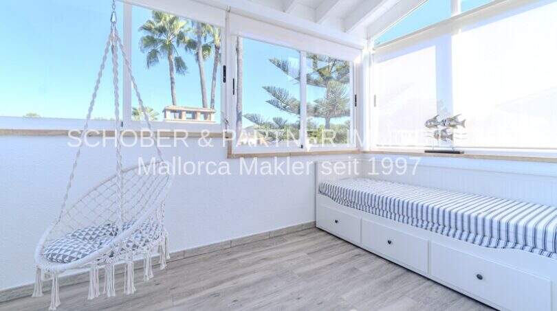 Helles Schlafzimmer mit Hängestuhl, Einzelbett und Palmenblick in mediterraner Villa Sa Coma