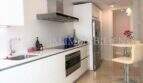 Moderne weiße Einbauküche mit Edelstahl-Dunstabzug, Induktionskochfeld und Frühstücksbar in Luxuswohnung Bendinat