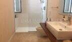 Modernes Badezimmer der Luxuswohnung Bendinat mit ebenerdiger Dusche, Wandhänge-WC und elegantem Holzwaschtisch.