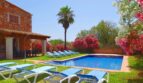 Finca Felanitx: Poolbereich mit Liegestühlen, Palme, blühenden Oleanderbüschen und Natursteinhaus