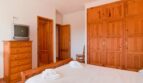 Schlafzimmer der Finca mit Doppelbett, Holzschrank, Kommode und TV in ruhiger Naturlage bei Felanitx.