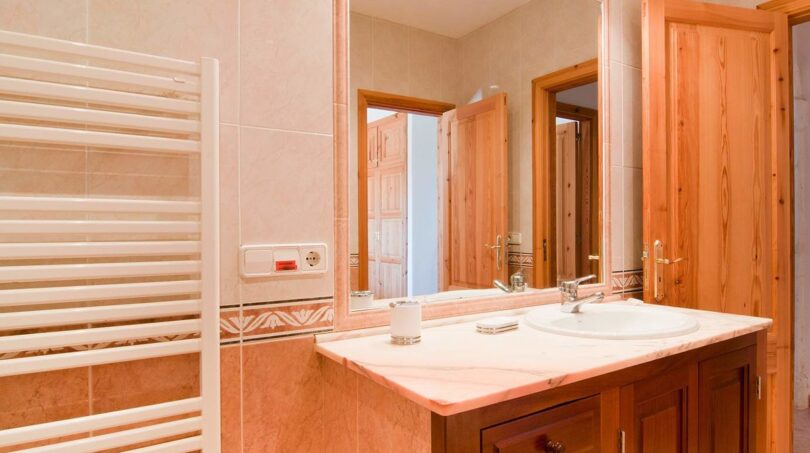 Badezimmer der Finca mit Marmor-Waschtisch, Holzschränken, großem Spiegel und Heizkörper in Felanitx