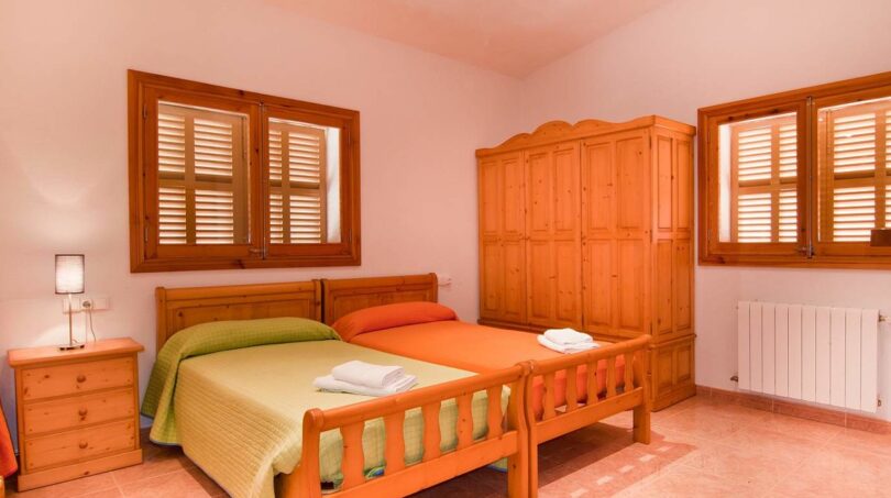 Helles Schlafzimmer der Finca mit Doppelbett, Holzmöbeln, Einbauschrank und Fensterläden in Felanitx.