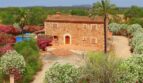 Finca aus Naturstein in Felanitx mit Pool, Palmen und blühenden Büschen in ruhiger Naturlage.