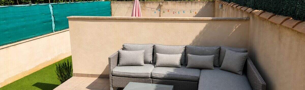 Sonnige Terrasse mit grauer Rattan-Lounge-Möbelgruppe und Lichterkette, Privatgarten in Santa Maria del Camí