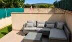 Sonnige Terrasse mit grauer Rattan-Lounge-Möbelgruppe und Lichterkette, Privatgarten in Santa Maria del Camí