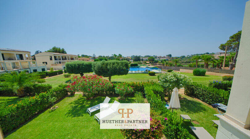 Gepflegter Gemeinschaftsgarten mit Pool, Sonnenliegen und Blumenbeeten beim Reiheneckhaus in Porto Cristo Novo.