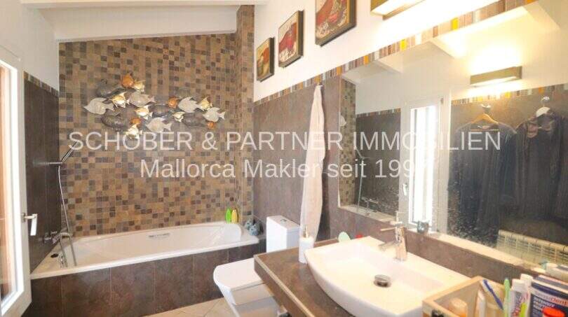 Modern bathroom with bathtub, mosaic tiles, sink and mirror in Villa Son Servera