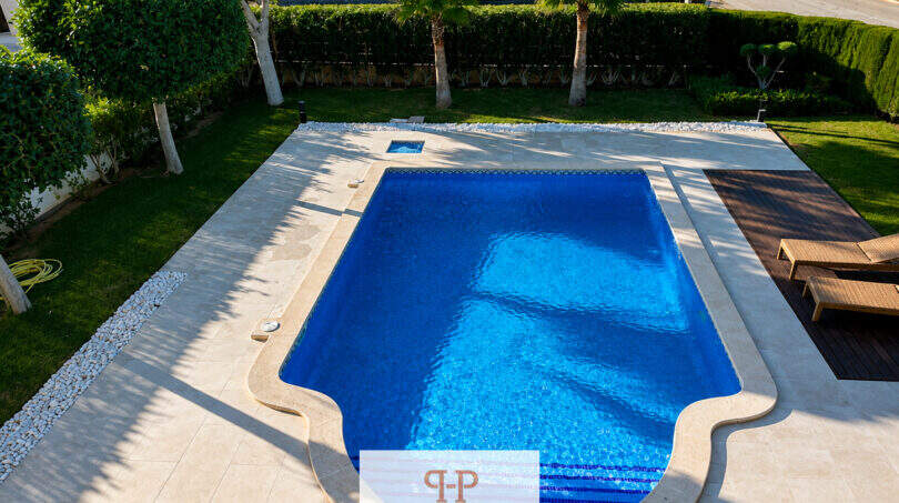 Gepflegter Außenpool mit blauem Wasser, Natursteinumrandung und Palmen der Villa Sa Torre in Llucmajor