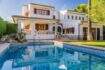 Außenansicht mediterrane Villa Sa Coma mit blauem Pool, weißer Fassade, Holzläden und üppigem Grün