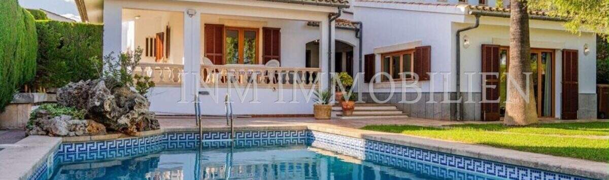 Außenansicht mediterrane Villa Sa Coma mit blauem Pool, weißer Fassade, Holzläden und üppigem Grün