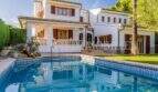Außenansicht mediterrane Villa Sa Coma mit blauem Pool, weißer Fassade, Holzläden und üppigem Grün