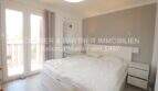 Dormitorio luminoso con cama doble, pared de acento gris y acceso a balcón en apartamento modernizado en Cala Ratjada