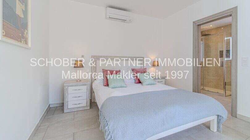 Helles Schlafzimmer der mediterranen Villa in Sa Coma mit Doppelbett, Klimaanlage und angrenzendem Bad.