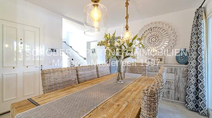 Elegantes Esszimmer der mediterranen Villa in Sa Coma mit Holztisch, Korbstühlen und stilvoller Pendelleuchte.