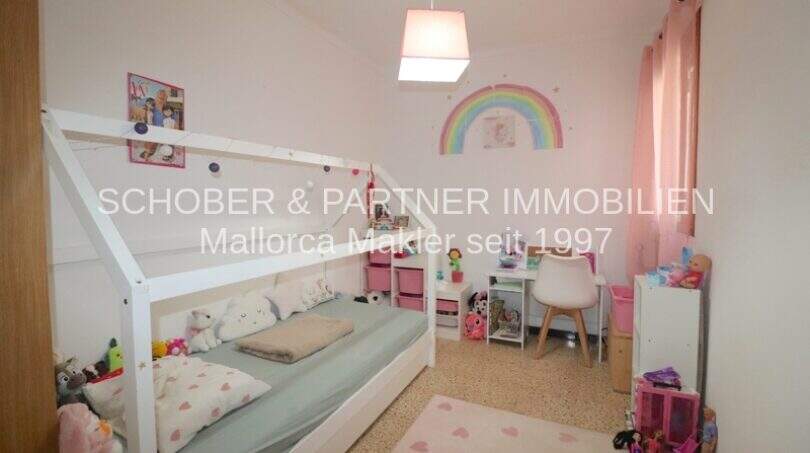 Habitación infantil con cama casita blanca, zona de juegos y decoración de pared con arco iris en cuidado apartamento de 4 habitaciones en Porto Cristo