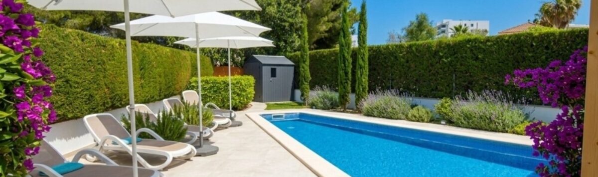 Sunny pool area with sun loungers, umbrellas and flower garden of the bungalow in Alcúdia.