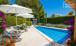 Sonniger Poolbereich mit Liegestühlen, Sonnenschirmen und Blumengarten des Bungalows in Alcúdia.