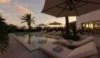 Luxuriöser Pool mit Sonnenliegen und Palmen bei Sonnenuntergang, Designvilla Cala Murada