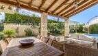 Überdachte Terrasse mit Holzbalken, Esstisch, Loungebereich und Pool in mediterraner Villa, Sa Coma
