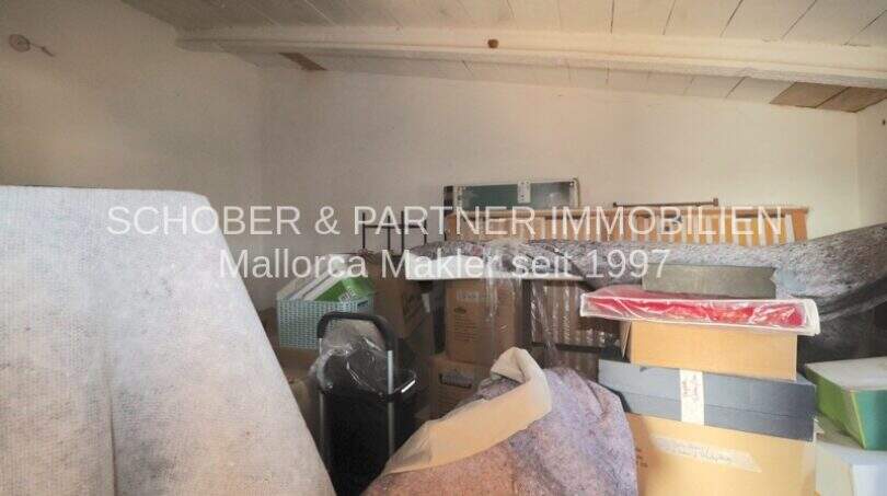 Abstellraum mit Holzbalkendecke, gefüllt mit Kartons und Lagergegenständen im Landhaus Port de Manacor
