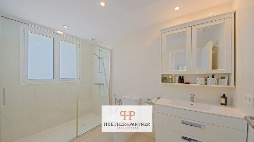 Helles Badezimmer im Reiheneckhaus Porto Cristo Novo mit Glasdusche, WC und modernem Waschtisch.