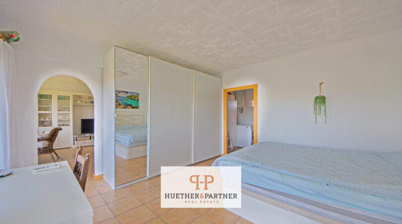 Helles Schlafzimmer mit Spiegelschrank, Terrakottaboden und Durchgang zum Wohnbereich im Apartment Cales de Mallorca