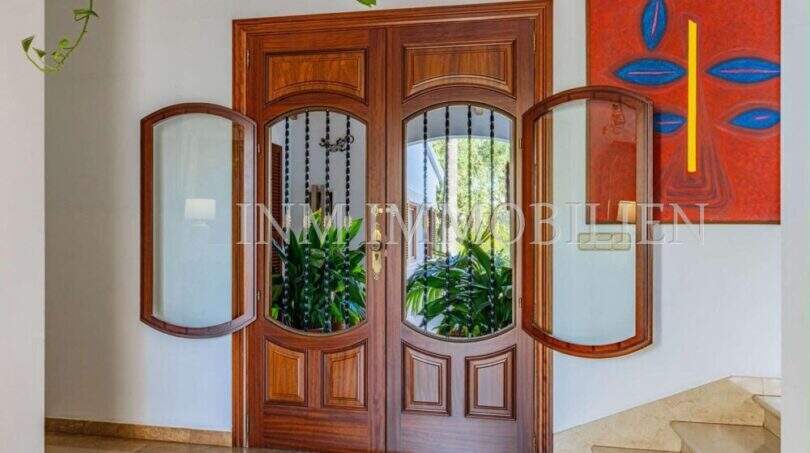 Eleganter Eingangsbereich mit Doppelholztür und Glasfenstern im mediterranen Einfamilienhaus in Sa Coma.