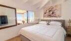 Bright bedroom with double bed, wooden beam ceiling and window with panoramic view in Son Servera