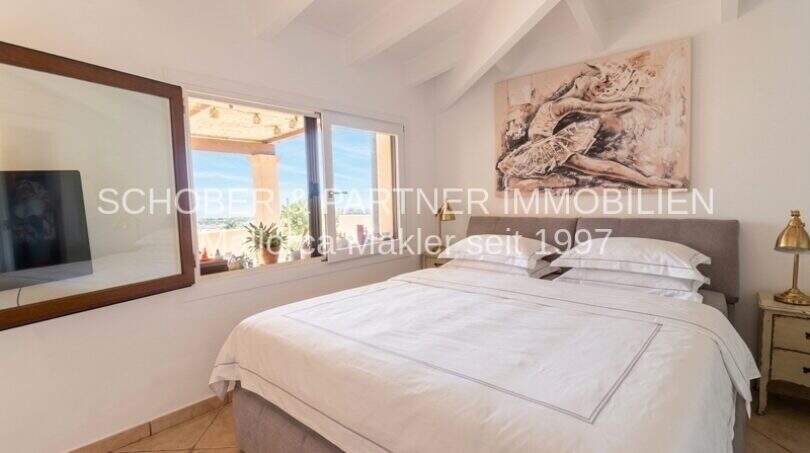 Bright bedroom with double bed, wooden beam ceiling and window with panoramic view in Son Servera