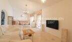 Helles Wohnzimmer mit weißen Sofas, Holztisch, Kronleuchter und TV im sanierten Landhaus in Port de Manacor
