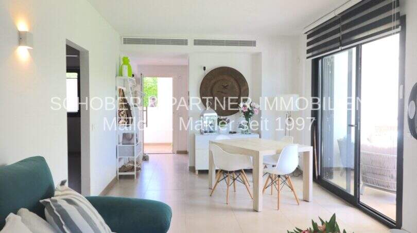 Heller Wohn-Essbereich der Eck-Wohnung in Sa Coma mit modernen Eames-Stühlen und Zugang zur Terrasse