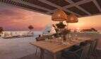 Dachterrasse mit Esstisch, Rattanlampen und Pergola bei Sonnenuntergang mit Meerblick in Cala Murada
