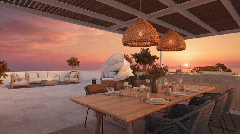 Dachterrasse mit Esstisch, Rattanlampen und Pergola bei Sonnenuntergang mit Meerblick in Cala Murada