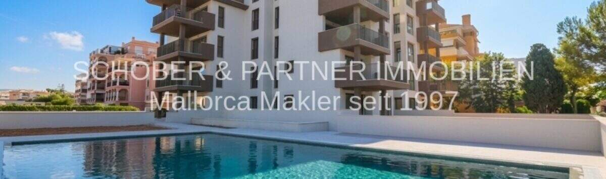 Modern apartment complex in Cala Millor with turquoise blue pool and balconies under sunny sky.