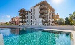 Moderne Appartement-Anlage in Cala Millor mit türkisblauem Pool und Balkonen unter sonnigem Himmel.