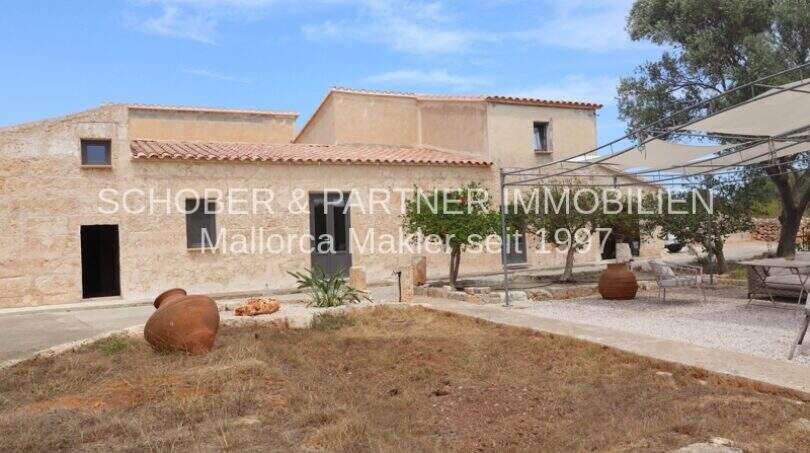 Außenansicht saniertes Landhaus Mallorca mit Natursteinmauern, Terrakottatöpfen und Sonnensegel im Innenhof