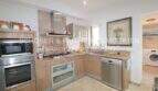 Modern L-shaped kitchen with wooden fronts, built-in appliances and granite countertop in Son Servera property