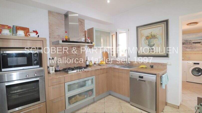 Modern L-shaped kitchen with wooden fronts, built-in appliances and granite countertop in Son Servera property