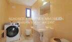 Badezimmer mit Waschmaschine, Wandtoilette und Naturstein-Waschtisch im sanierten Landhaus Port de Manacor