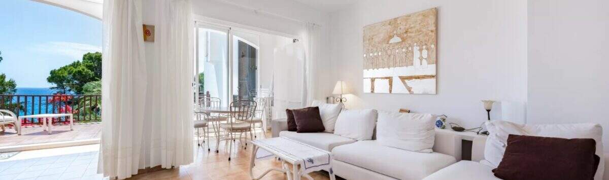 Helles Wohnzimmer mit weißen Sofas, Meerblick-Terrasse und Fliesen in Erdgeschosswohnung Cala Mandia