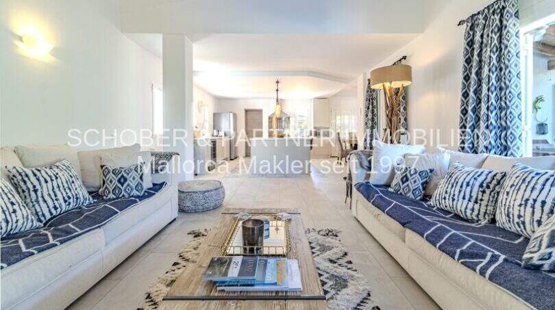 Geräumiges Wohnzimmer der mediterranen Villa mit blauen Sofas, Designerkissen und elegantem Tisch in Sa Coma