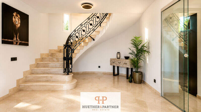 Eleganter Eingangsbereich einer Villa in Sa Torre mit Marmortreppe, Schmiedeeisengitter und Glasfront.