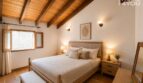 Schlafzimmer mit Holzbalkendecke, Doppelbett, Wandleuchten und Terrakottaboden im Stadthaus Petra