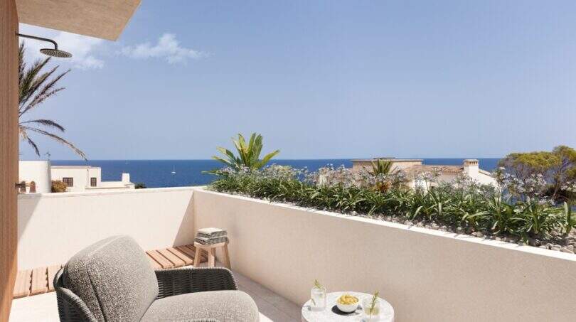 Sonnige Dachterrasse mit Rattansessel, Meerblick, mediterranen Pflanzen und Außendusche in Cala Murada
