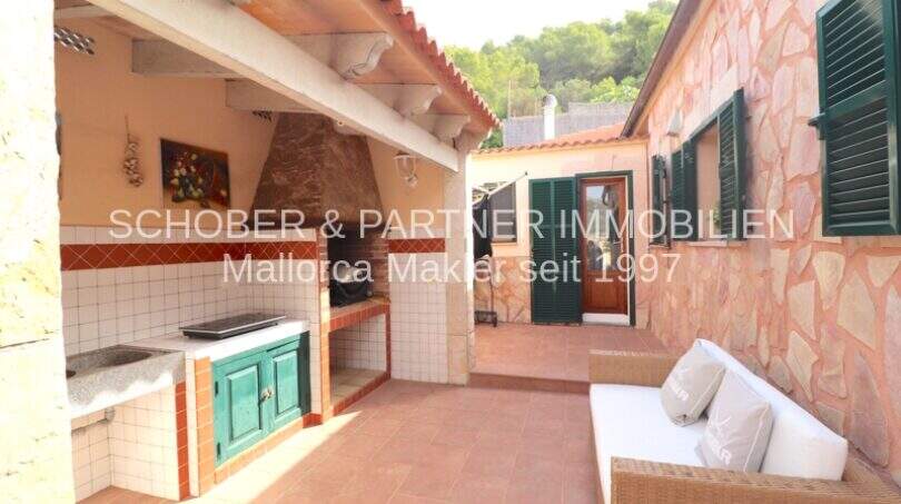 Covered terrace with outdoor kitchen, grill area and lounge sofa at natural stone house in Son Servera