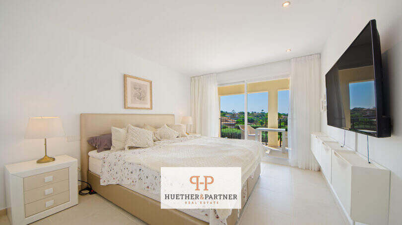 Helles Schlafzimmer mit Doppelbett, TV und Balkon mit Grünblick im Reiheneckhaus Porto Cristo Novo.