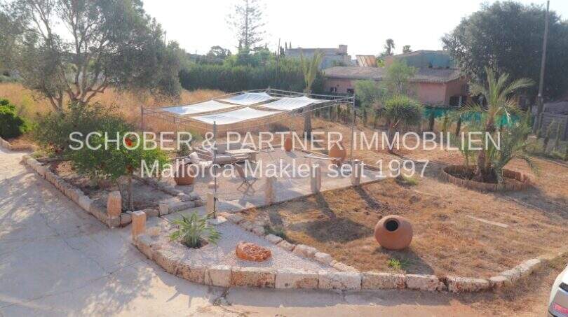Gepflegter Gartenbereich eines Landhauses in Portocristo mit Sonnensegel, Natursteinbegrenzung und mediterranen Pflanzen.