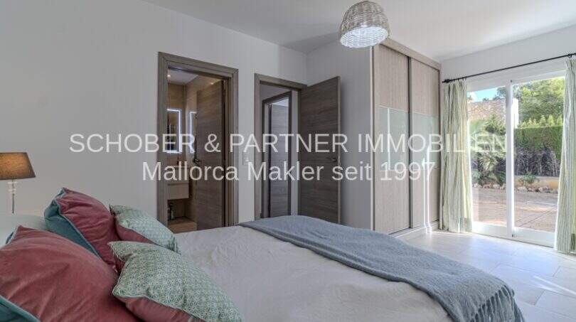 Helles Schlafzimmer der mediterranen Villa in Sa Coma mit Einbauschrank, En-suite-Bad und Terrassenzugang.