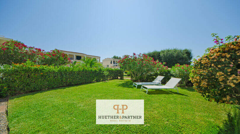Gepflegter Garten mit Liegestühlen und bunten Blüten beim Reiheneckhaus in Porto Cristo Novo.